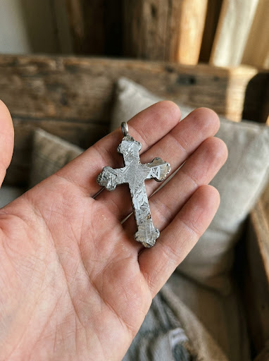 The Oath Cross held in the palm of a hand, showing its scale